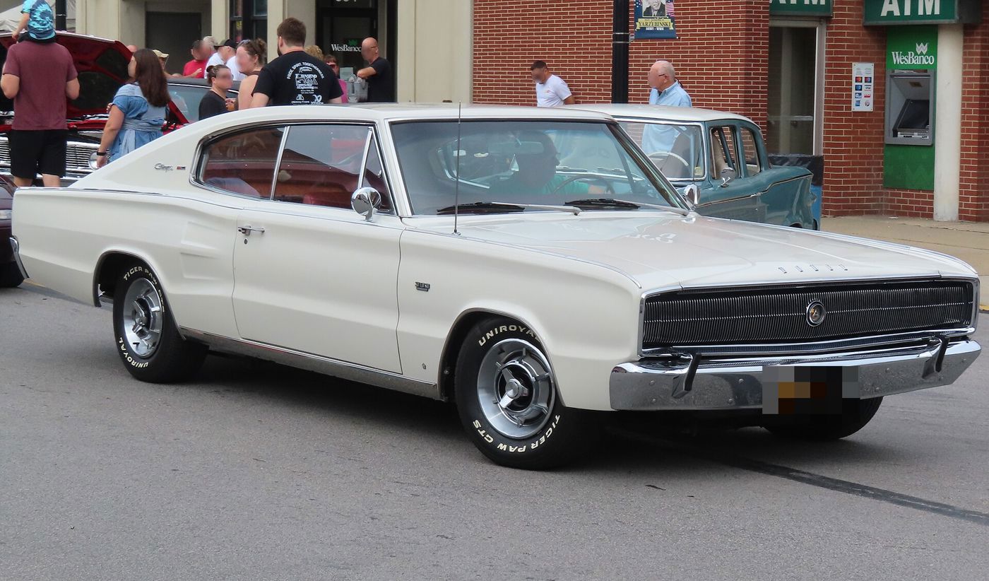 White 1966 Dodge Charger fastback with its full-width hidden-headlamp grille, front three-quarter on a town street