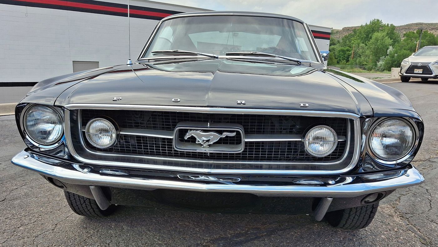 Head-on view of a black 1967 Ford Mustang with running-horse grille emblem and GT fog lamps in the grille