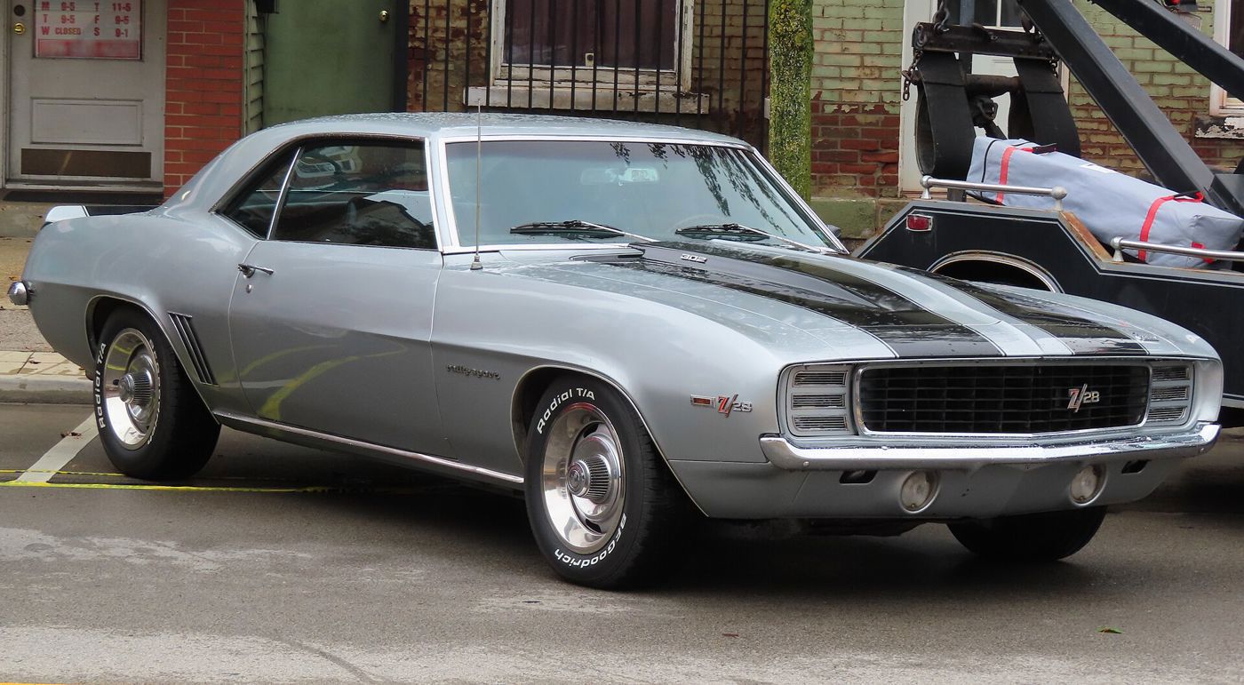 Silver 1969 Camaro Z/28 with black hood and deck stripes, Z/28 grille badge and hidden headlamps, front three-quarter