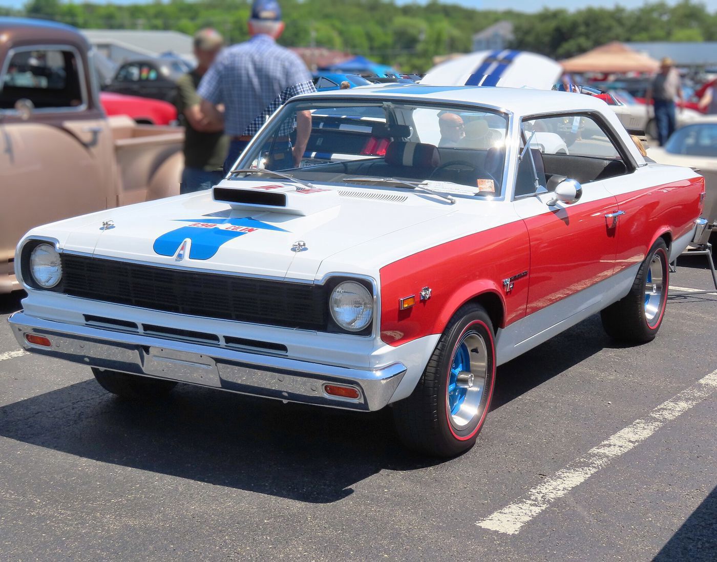 White, red and blue 1969 SC/Rambler hardtop with the blue hood arrow and ram-air scoop, front three-quarter at a cruise-in