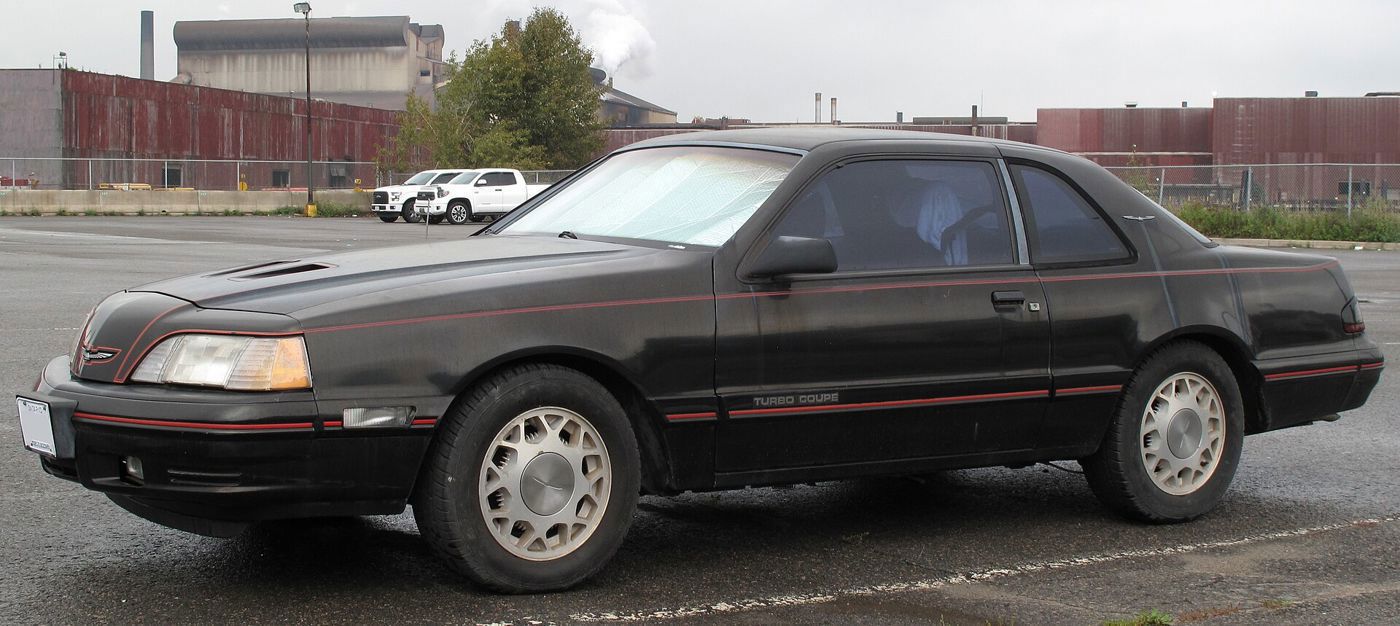 Black 1987 Ford Thunderbird Turbo Coupe with red pinstripe and Turbo Coupe lettering, side view in a lot