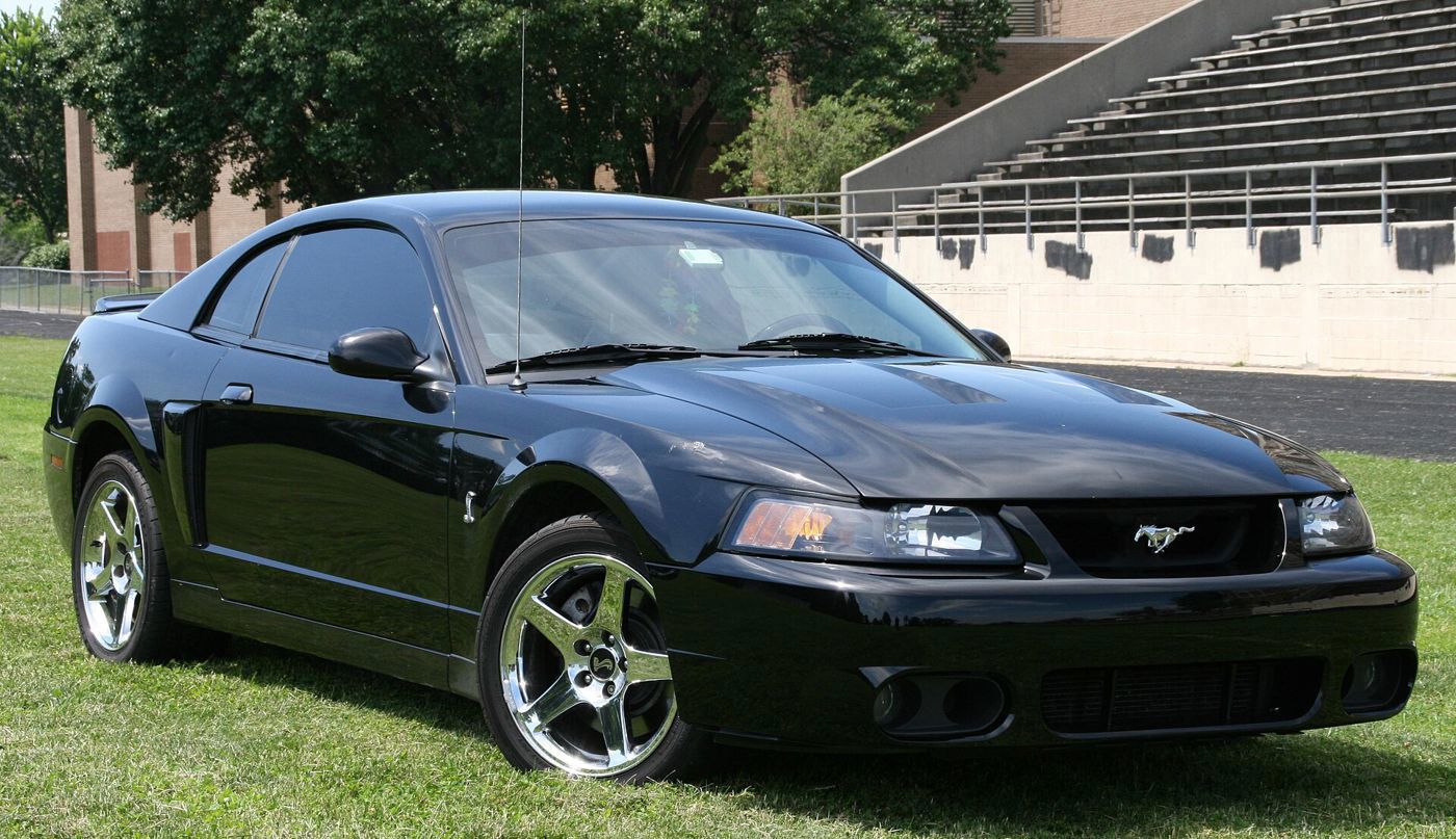 Black 2003-2004 Mustang SVT Cobra coupe with five-spoke wheels, front three-quarter on grass