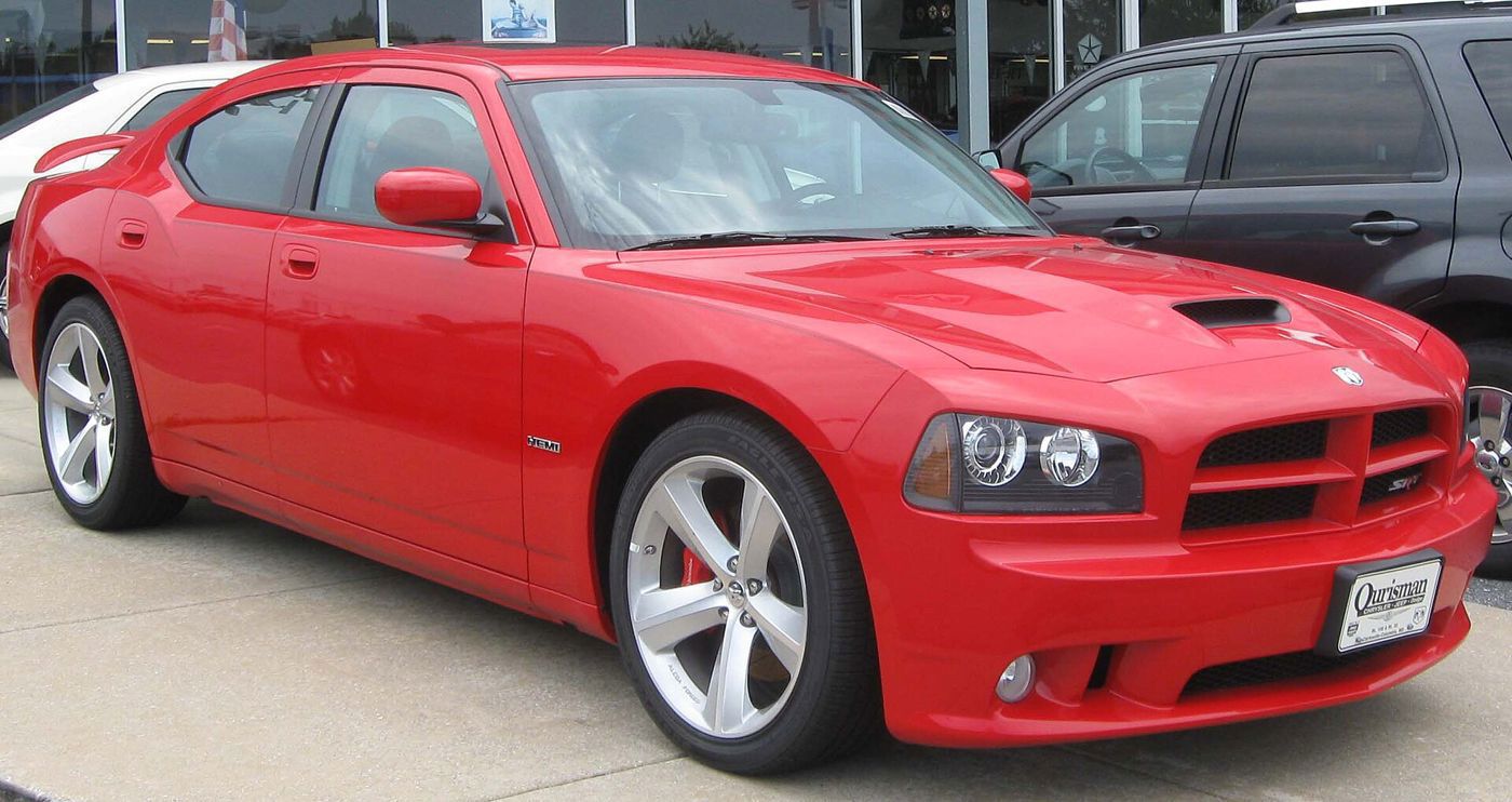 Red 2010 Dodge Charger SRT8 sedan with hood scoop and SRT8 grille badge, front three-quarter on a dealer lot