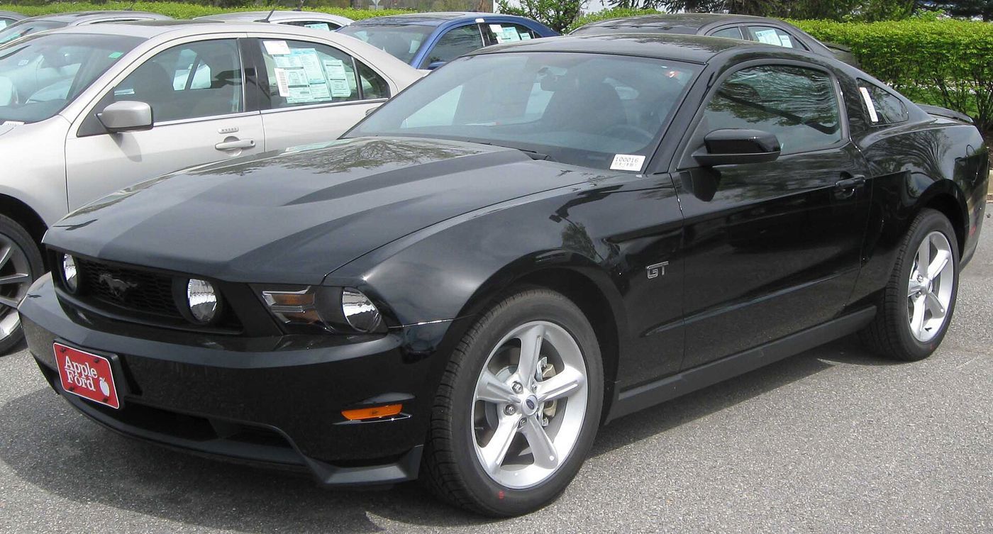 Black 2010 Ford Mustang GT coupe with GT fender badge, front three-quarter on a dealer lot
