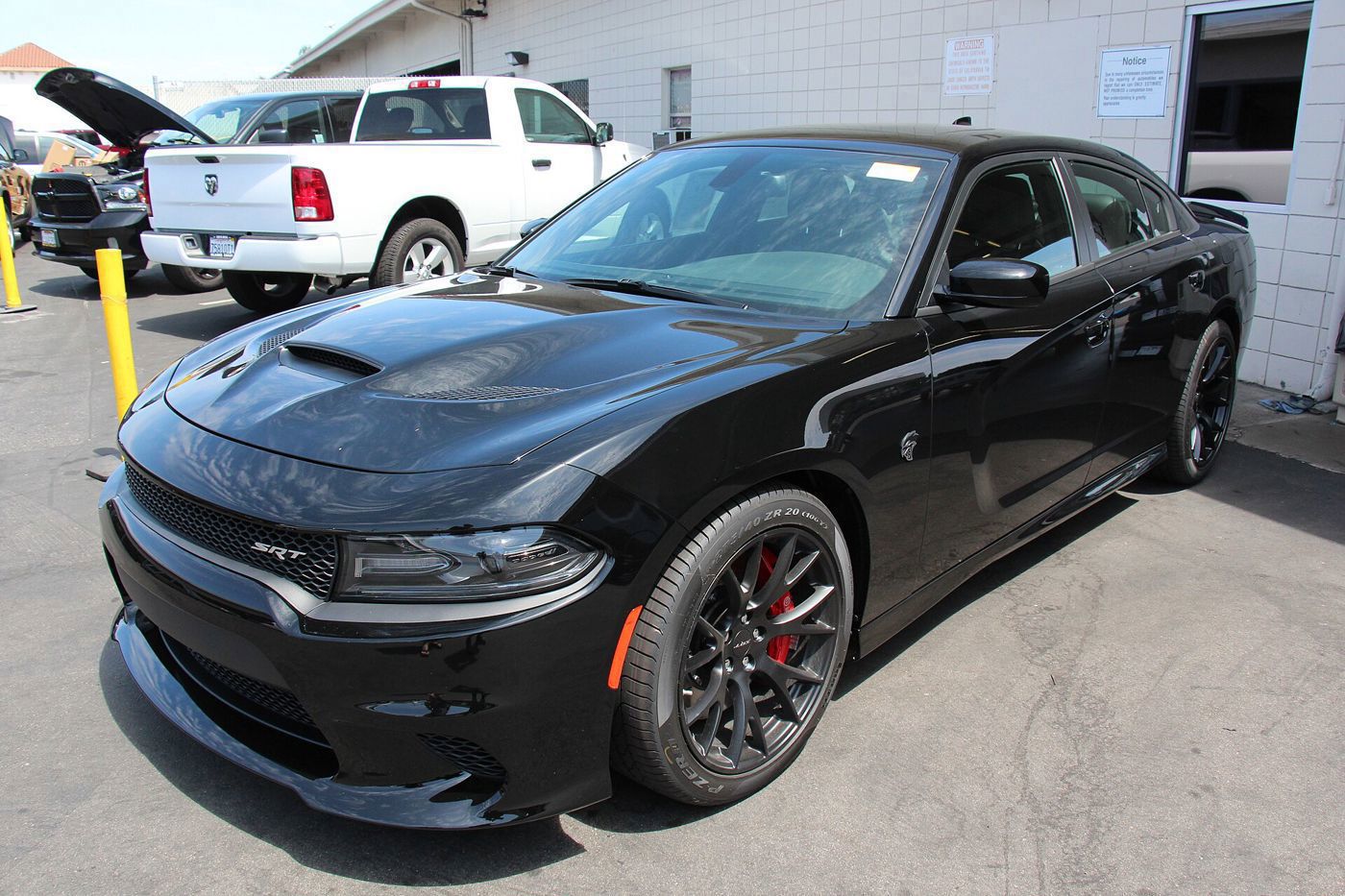 Black 2015 Charger SRT Hellcat sedan with SRT grille badge and red brake calipers, front three-quarter on a dealer lot