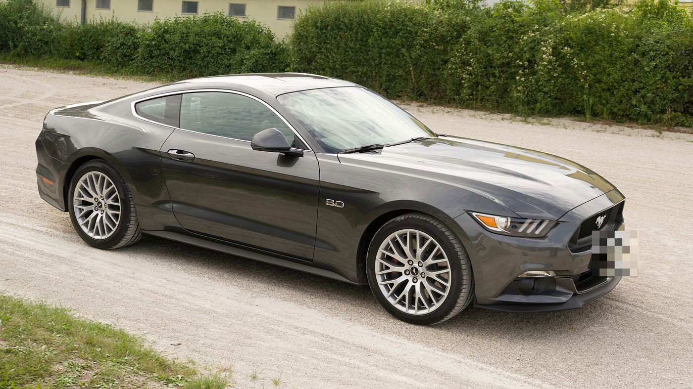 Dark gray 2015 Mustang GT fastback with 5.0 fender badge, front three-quarter on a gravel road