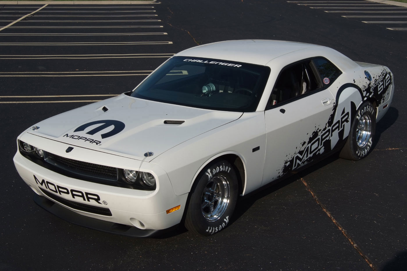 White Dodge Challenger drag car with black Mopar graphics and drag slicks in a parking lot