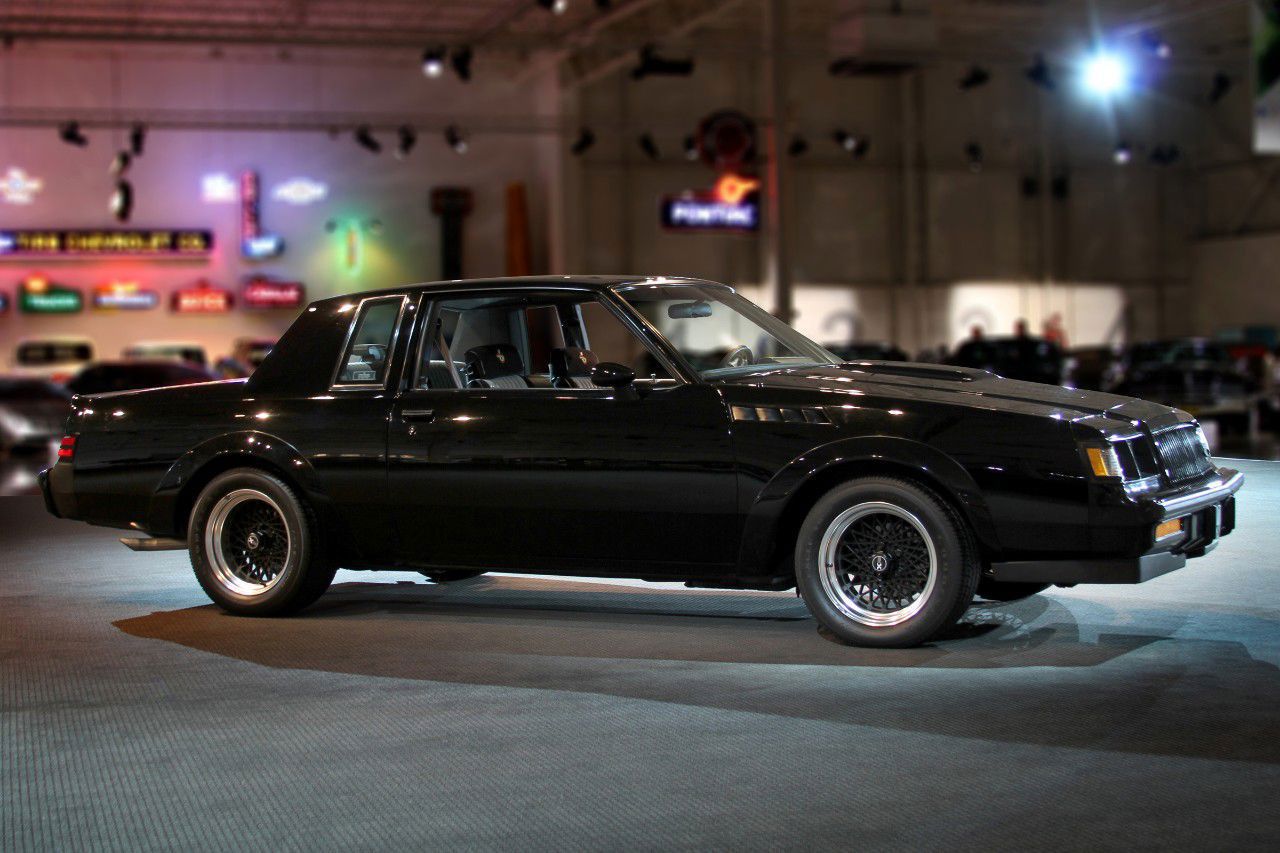 Black 1987 Buick GNX coupe with mesh wheels shown from the side in the GM Heritage Center hall
