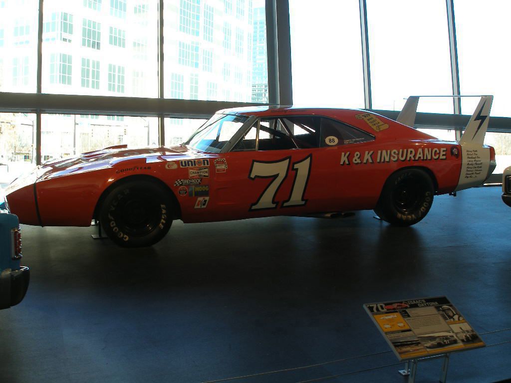 Orange number 71 Dodge Charger Daytona with K&K Insurance lettering and tall rear wing, displayed indoors