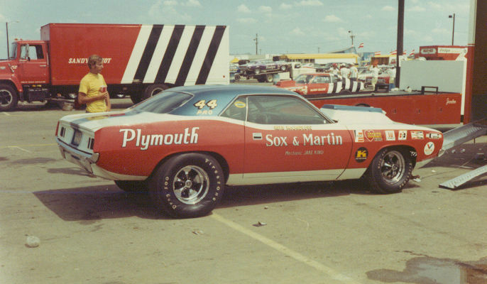 Red and white Plymouth Cuda with Sox & Martin lettering and 44 Pro on the windshield in a drag strip pit