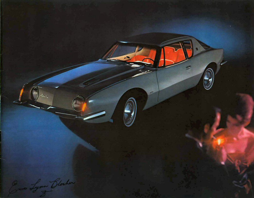 Brochure page with a silver 1963 Avanti from above the front three-quarter on a dark background, a couple at lower right