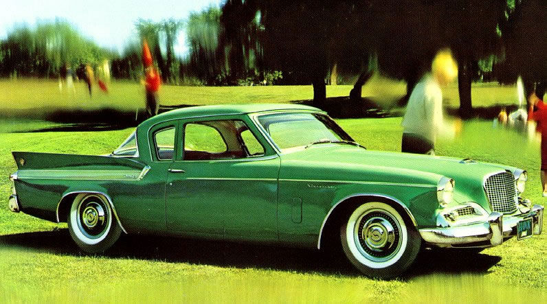 Brochure photo of a green 1961 Studebaker Hawk coupe on grass, a golfer blurred behind